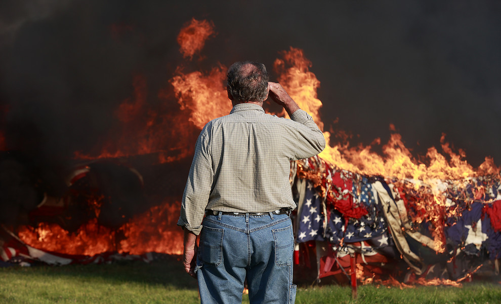 General News - 1st place - Lance James salutes an estimated 10,000 American flags as they burn during the annual flag retirement ceremony at American Legion Post 286 in New Carlisle. People and businesses from around the country send their worn out flags to the American Legion Post so they can be disposed of properly on Flag Day.  (Bill Lackey / Springfield News-Sun)