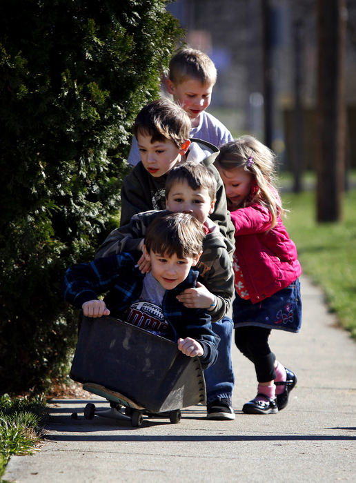 Feature - 3rd place - Judah Evans (bottom) and Justin Carney (behind him) get a push from Judah's brother Isaac Evans, Landon Peterson (top) and Justin's sister Cameron Carney (right) on the sidewalk next to High Street in Harrisburg. The group was taking advantage of the sunshine by using Landon's idea to put different items on top of a skateboard to see how far they could make it down the sidewalk. This particular trip failed soon after launch. (Jonathan Quilter / The Columbus Dispatch)