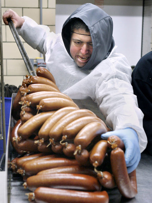 Feature - HMDon Lamonica takes bologna off a rail, that the meat hung from while being smoked, prior to being packaged at Troyer's Trail Bologna factory in Trail. The company is celebrating its 100th anniversary. (Scott Heckel / The (Canton) Repository)