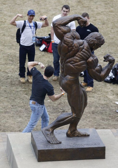 Story - 2nd place - Brian Burton of Macomb, Mich. (top left) gives posing advice to Alberto Vega of Chihuahua, Mexico as he prepares to have his picture taken by the bronze statue of Arnold Schwarzenegger prior to the finals of the Arnold Classic bodybuilding competition at Veterans Memorial. (Adam Cairns / The Columbus Dispatch)