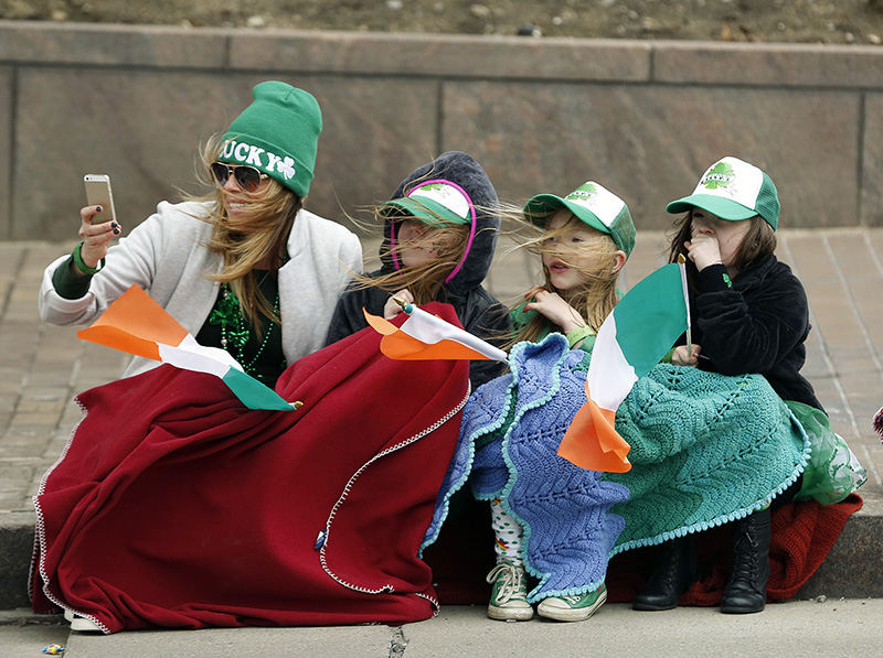 General News - 2nd place - On a cold and windy day Bridget Dolan (left) takes pictures of the parade while her daughter, Gretchen Piatt (left center) and her class classmates Reese Tucker (right center) and Mya Montgomery watch during the 2015 St. Patrick's Day Parade. (Kyle Robertson / The Columbus Dispatch)