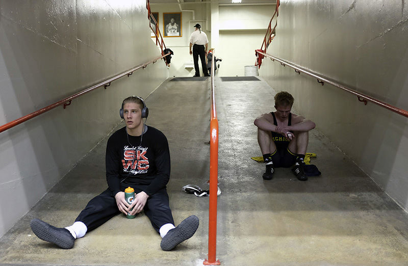 Story - HM - Michigan's George Fisher (right) sits in the entrance way after losing in overtime to Purdue's Nick Lawrence ending his season in a 141 lb match while Rutger's Hayden Hrymack (left) watches action during the 2015 Big Ten Wrestling Championship at St. John Arena in Columbus.   (Kyle Robertson / The Columbus Dispatch)