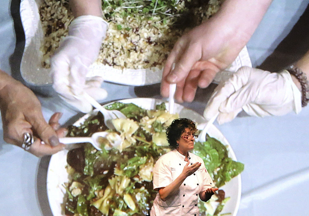 Feature - 1st place - Chef Sherry Schie of Shy Cellars talks about bow tie cajon chicken salad and cauliflower rice pilaf she created during The Taste of Massillon Cooking Show. Behind her is an overhead video that shows her assistants sampling the dishes. (Scott Heckel / The Repository)