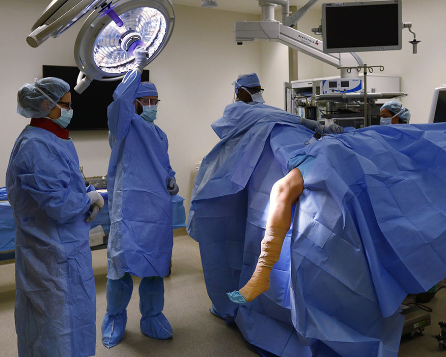 General News - 1st place - Ohio State Wexner is the first in the Midwest to implant a device that works to alleviate knee pain and prevents knee replacement surgery. The surgery team prepares for orthopedic surgeon Chris Kaeding (not pictured) to operate and implant the device on a patient at the Ohio State Jameson Crane Sports Medicine Institute. (Fred Squillante / The Columbus Dispatch)