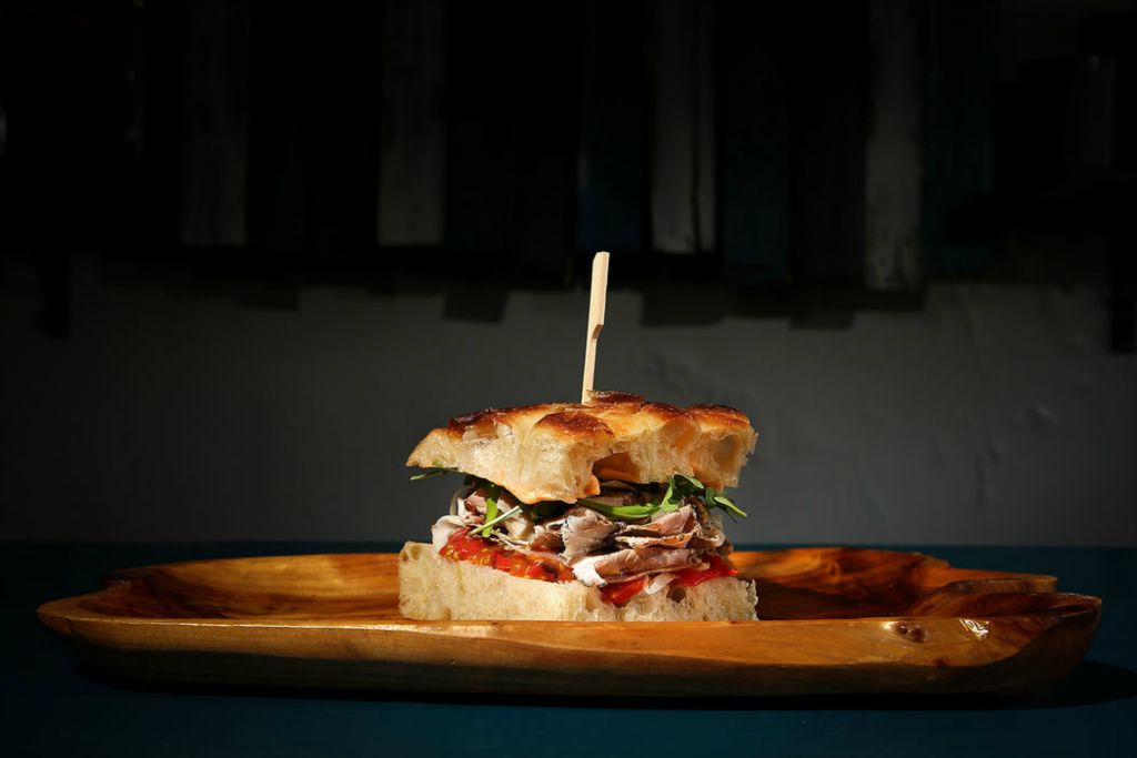 Illustration - 1st place - The porchetta focaccia sandwich, tuscan spiced pork belly and shoulder, fennel, arugula and hot pepper aioli, pictured, at The Wheel in Cincinnati's Oakley neighborhood.  (Kareem Elgazzar / The Cincinnati Enquirer)