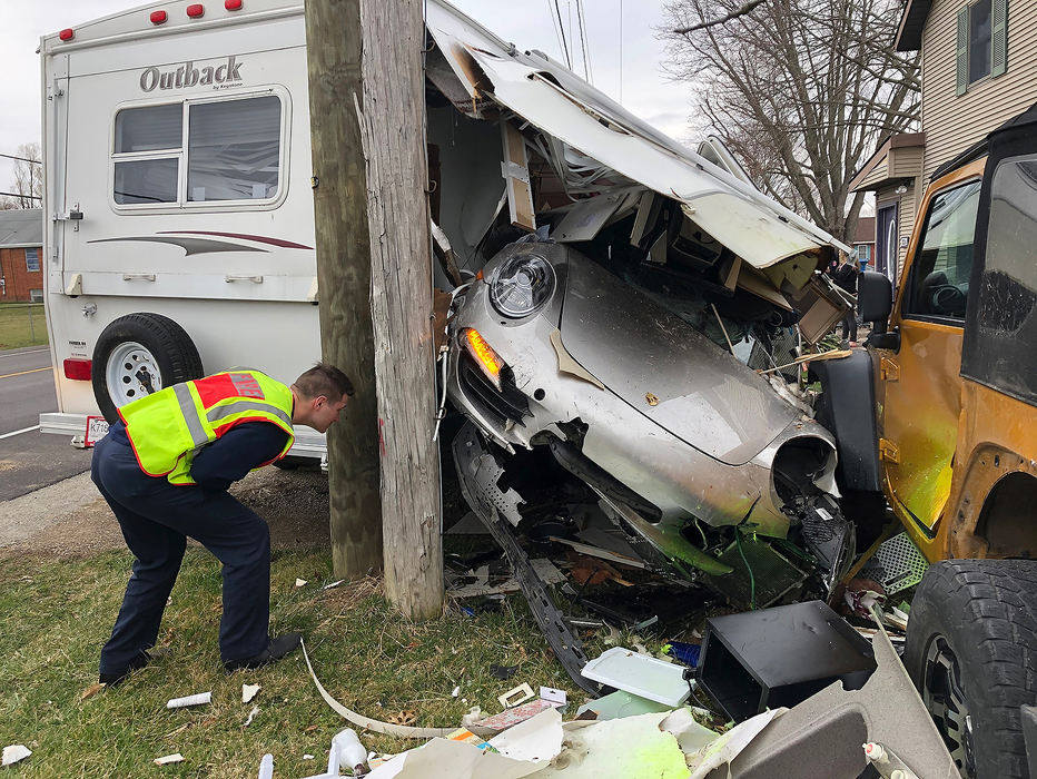 Spot News - 1st place - The driver of a Porsche drove off the left side of the road in the three thousand block of Springfield-Xenia Road and struck two mailboxes, a fence, two cars and a camper parked in front of a house. The driver was not injured in the crash that left the Porsche inside the camper.  (Bill Lackey / Springfield News-Sun)