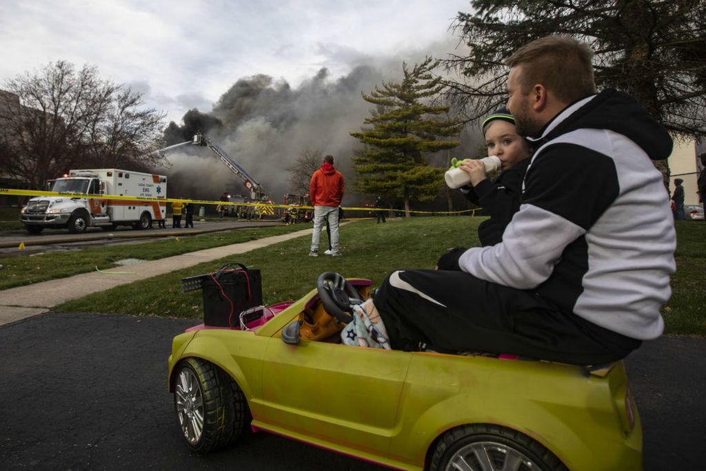 Feature - 1st place - Josh Matanick and his son Simon, 2, sit in an electric toy car and watch as Toledo Fire and Rescue battle an apartment fire on the 5900 block Cresthaven Lane. (Rebecca Benson / The Blade)