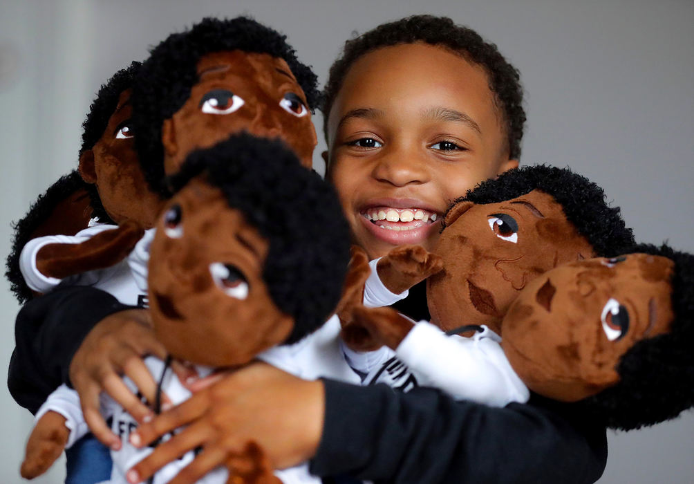 Portrait - 1st place - Demetrius "Dee" Davis, the eight-year-old CEO of Our Brown Boy Joy, grins as he peeks over an arm load of his company's "My Friend" dolls. The 18-inch plush dolls were created in his likeness, with his black curly hair, a white and tan Timberland boots. (Jeff Lange / Akron Beacon Journal)