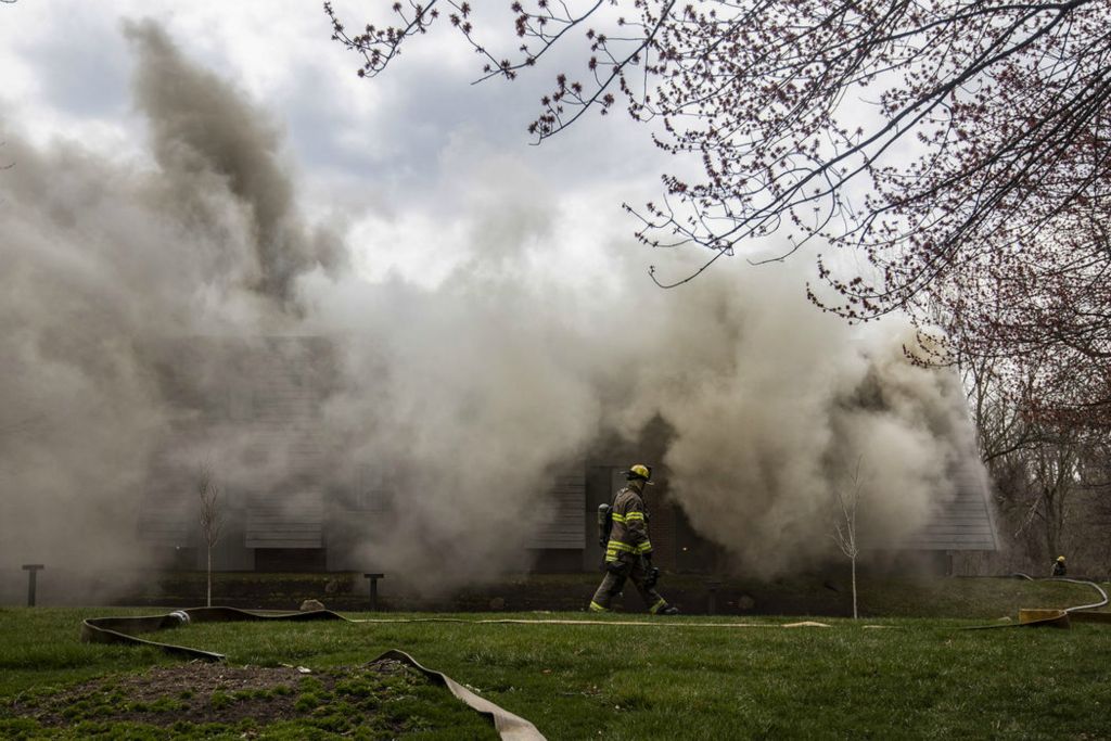 Spot News - 1st place - A firefighter walks across the lawn as area firefighters battle an apartment fire on the 5900 block Cresthaven Lane. The fire began in the attic and quickly spread throughout the rest of the apartment building due to high winds. Residents were safely evacuated and there were no reported injuries.  (Rebecca Benson / The Blade)