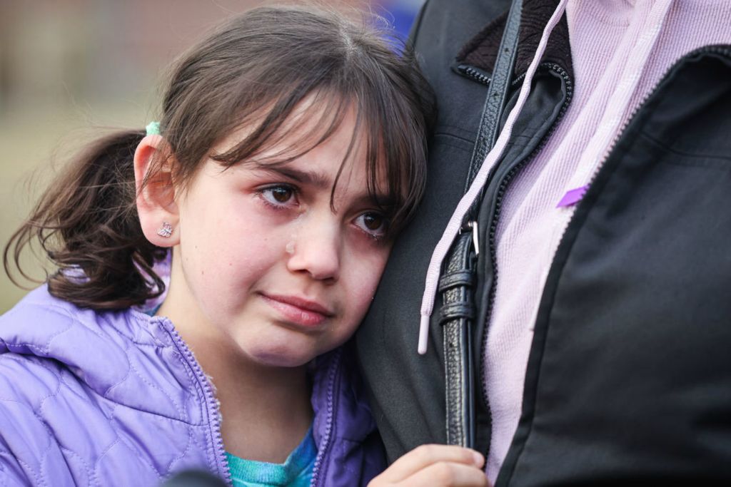 General News - 2nd place - Sawson Grodi, 8, cries as she holds her mother, Lana Tabbalat, at a public gathering at The Violence Against Women Memorial Rock in Toledo to honor the lives of domestic abuse victims Ashley Darrington, Nora Pryba, Whitney Wade, and Sarah Schulte. (Lizzie Heintz / The Blade)