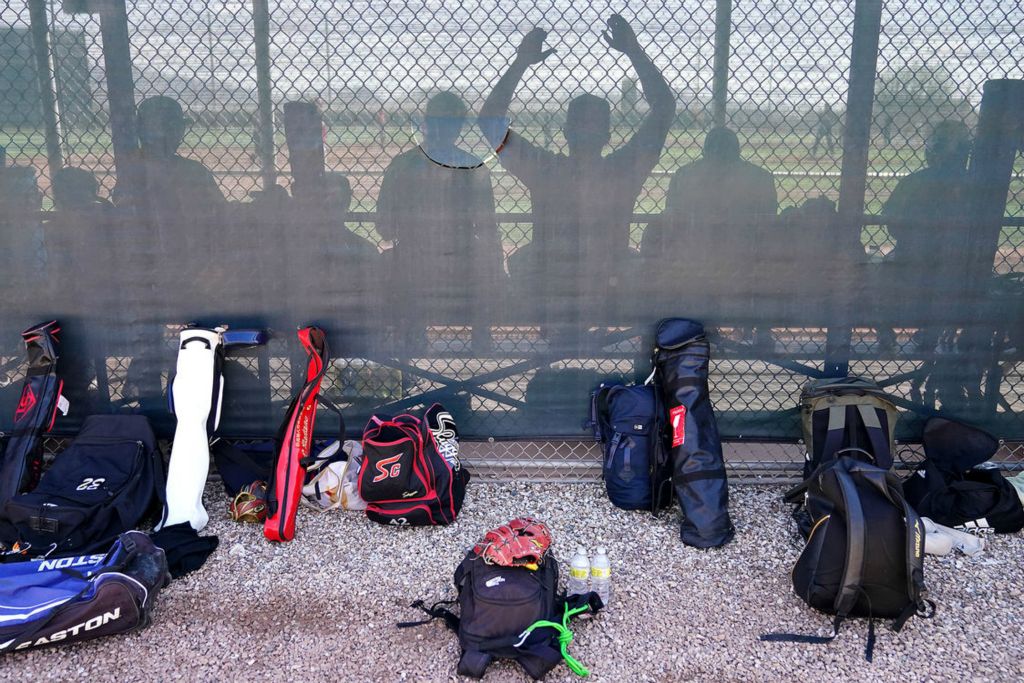 Sports Feature - HM - Members of the Japanese team Asian Breeze sit in the dugout as they play a game against Cincinnati Reds’ minor-league players at the baseball team's spring training facility in Goodyear, Ariz. (Kareem Elgazzar / The Cincinnati Enquirer)