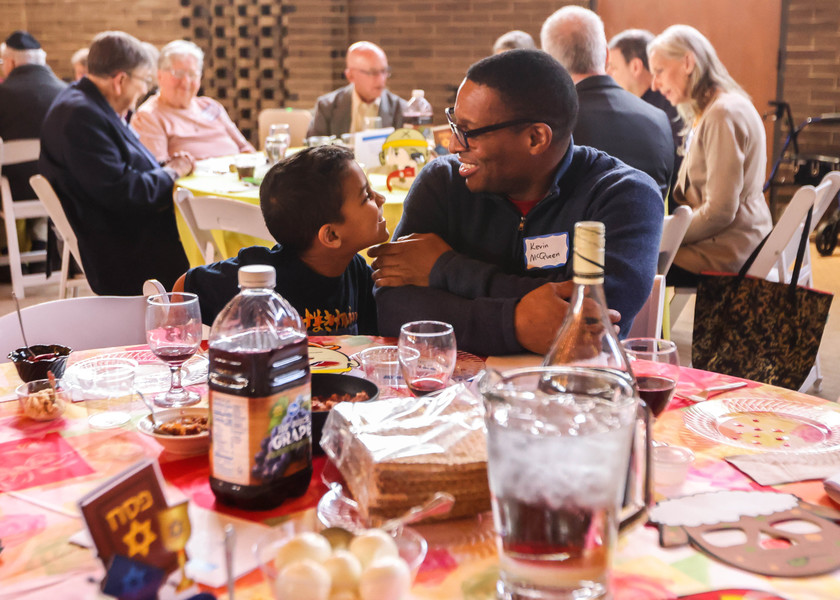 Feature - 2nd place - Temple member Micah McQueen, 8, (left) turns to father Kevin McQueen, who takes a break from moderating the table, at an interfaith Seder hosted by the Jewish Federation for non-Jewish community members ahead of Passover at Wildwood Manor House in Sylvania. (Isaac Ritchey / The Blade)