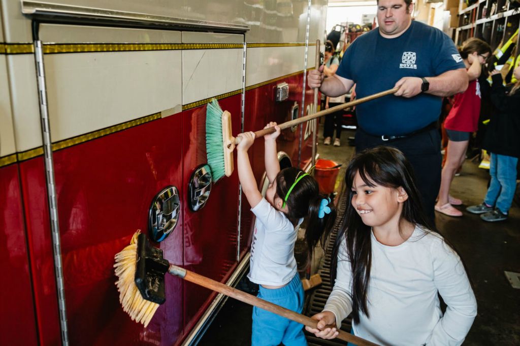 Feature - 2nd place - Ziola Goodall, 7, and her sister Tala, 3, along with Dover Firefighter Matt Hamsher help to wash a fire department squad in the bay of the downtown fire station as part of the Dover Acts of Kindness project. (Andrew Dolph / The Times Reporter)