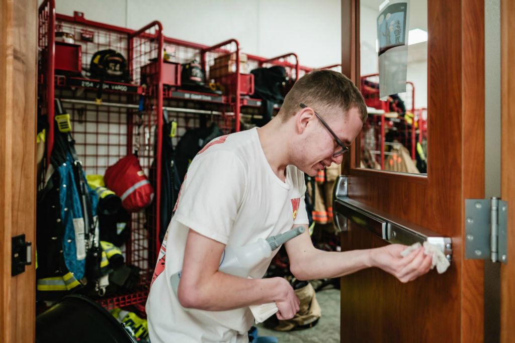 Feature - HM - Jehred Bennett, 20, cleans crash bars and door handles as part of his janitorial duties at the New Philadelphia Fire Department fire station, where he works part time. When Jehred Bennett was born nine weeks premature in 2003, he weighed just 2 pounds 7 ounces. Now at age 20,  Bennett is an outgoing, friendly, personable young man. Though he is developmentally disabled and has autism, that hasn't slowed him down.  (Andrew Dolph / The Times Reporter)