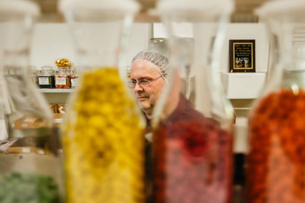 Feature - HM - John Gibbs, co-owner of Eiler Candy Shop in Dover, looks over some of his product while assisting a customer. Chocolate prices have surged 108% since Jan. 1 because of climactic factors in West Africa. Coupled with a surge in sugar prices as well, chocolatiers such as Gibbs have had to pass price increases to the customer. (Andrew Dolph / The Times Reporter)