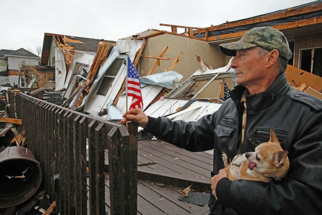 Spot News - 2nd place - After finding a small flag in the rubble of his house, Ron Watt sticks it in a crack on railing of his deck. Ron's house was one of dozens of homes destroyed by a tornado in Lakeview.  (Bill Lackey / Springfield News-Sun)