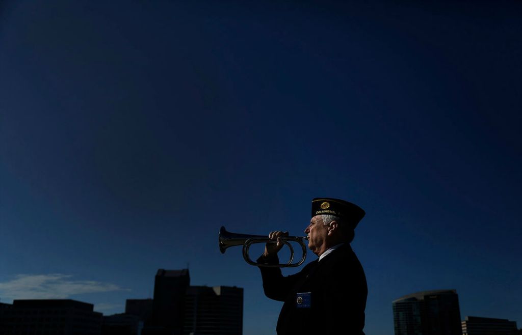 Feature - 2nd place - Richard Rozzell of American Legion Navy Marine Post 276 plays "Taps" after lowering of a flowered anchor off of the Broad St. bridge in downtown Columbus during Memorial Day. This was the 100th year that the post has provided this service on the Scioto River, through wars and crises and they have never missed a year. (Kyle Robertson / The Columbus Dispatch)