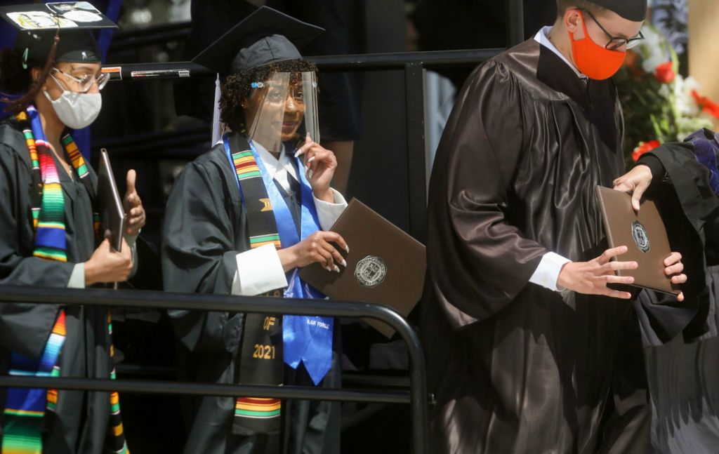 Oceania Alexis Mack (center) wears a face shield while receiving her baccalaureate degree during the commencement ceremony at Doyt Perry Stadium at Bowling Green State University.