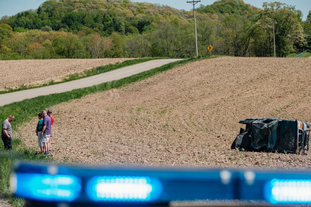 Spot News - 3rd place - The driver of a pickup truck, at left in grey shirt, which rolled approximately 30 yards into a cornfield, stands with family members on Ridge Rd. NE near University Dr.,  in Goshen Township. No specific cause of the crash was reported by the Ohio State Patrol Trooper on scene conducting the investigation.  (Andrew Dolph - The Times Reporter)  