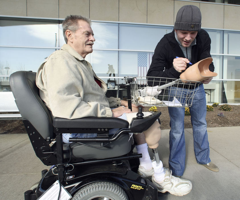 General News - HM - Columbus Blue Jackets right wing Derek Dorsett signs the prosthetic leg of Victor Hibbs outside the Columbus VA Ambulatory Care Center in Columbus. Hibbs is an Air Force veteran from the Vietnam War and was at the center to pick up his new prosthetic leg. Hibbs was sitting outside the center smoking and chatting with a few veterans, not being familiar with the Jackets, he wondered about hockey players who fight when Jacket's Dorsett was leaving the center for an earlier autograph session inside. After a hand shake Hibbs asked Dorsett to sign his leg.  (Neal C. Lauron / The Columbus Dispatch)