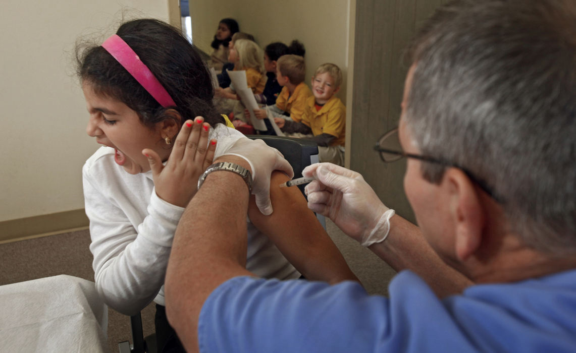 General News - 3rd placeRodina Elasbali (left) reacts to the sting of a flu shot administered by Jim Black, a LPN with the Columbus Public Health Department. Rodina , a second grader at Noble Academy, was one of 9 students to get vaccinated.  (Tom Dodge / The Columbus Dispatch)