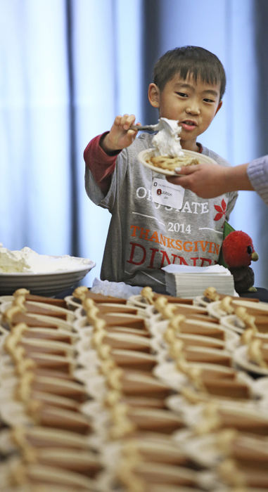 Story - 3rd place - Jiwon Jim, 8, attended the annual Ohio State University Thanksgiving Day dinner held in the Ohio Union with his parents and helped dole out whipped cream for the pumpkin pie.  The annual event is attended by hundreds of students, family members and university employees .   (Chris Russell / The Columbus Dispatch)