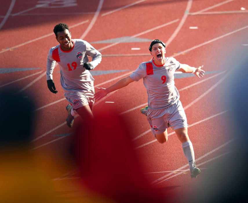 Sports Feature - HM - Ohio State's Danny Jensen runs toward the OSU fan section after scoring the equalizer goal late in the 2nd half of their NCAA tournament match against Dayton. Jensen is chased by fellow team mate Marcus McCreary. The Buckeyes advanced to the NCAA sweet 16 after defeating Dayton by way of Penalty kicks (4-3). (Erik Schelkun / Elsestar Images)