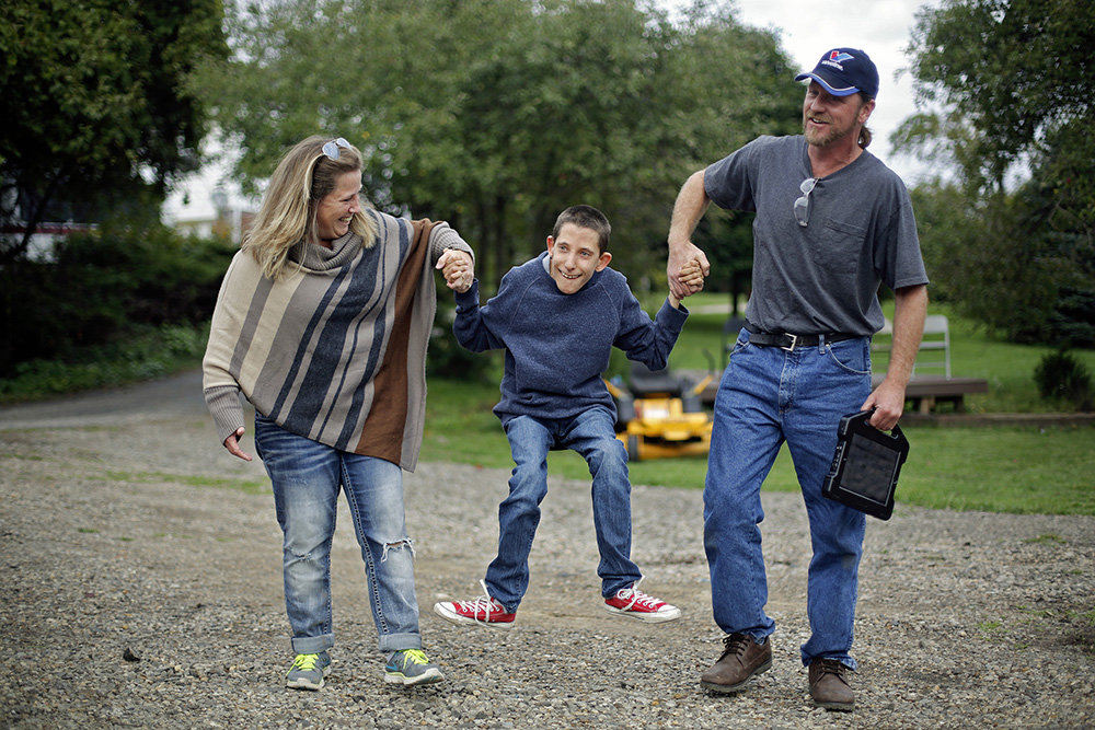 Story - 2nd place - Rocky Grimes (right) and Valerie Fuller (left) swing Valerie's son Michael while walking to the car after his go-cart session on a farm in Mechanicsburg. Valerie said, smiling as she watches her son drive towards the setting sun. "Serendipity, fate, whatever you want to call it.  Rocky was meant to be in our lives. We know that. He is a savior."  (Kyle Robertson / The Columbus Dispatch)