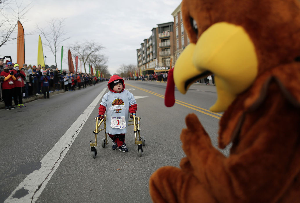 AGeneral News - HM - After all the other kids had crossed the finish line, and with some encouragement from the turkey mascot and hundreds of spectators, Austin Evans, 3, who requires a walker to aid his movement, makes his way to the finish line for the Tot Trot at the annual Chase Columbus Turkey Trot on Thanksgiving Day in Upper Arlington. (Adam Cairns / The Columbus Dispatch)