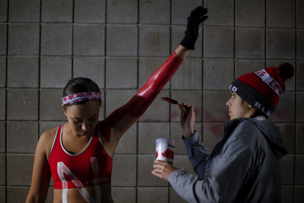 SPSports Feature - 1st place - Ohio State freshman Bailey Mayes (left) raises her arm as freshman Alli Payne applies body paint outside the Block O student section before a game against Illinois at Ohio Stadium in Columbus. (Joshua A. Bickel / The Columbus Dispatch)