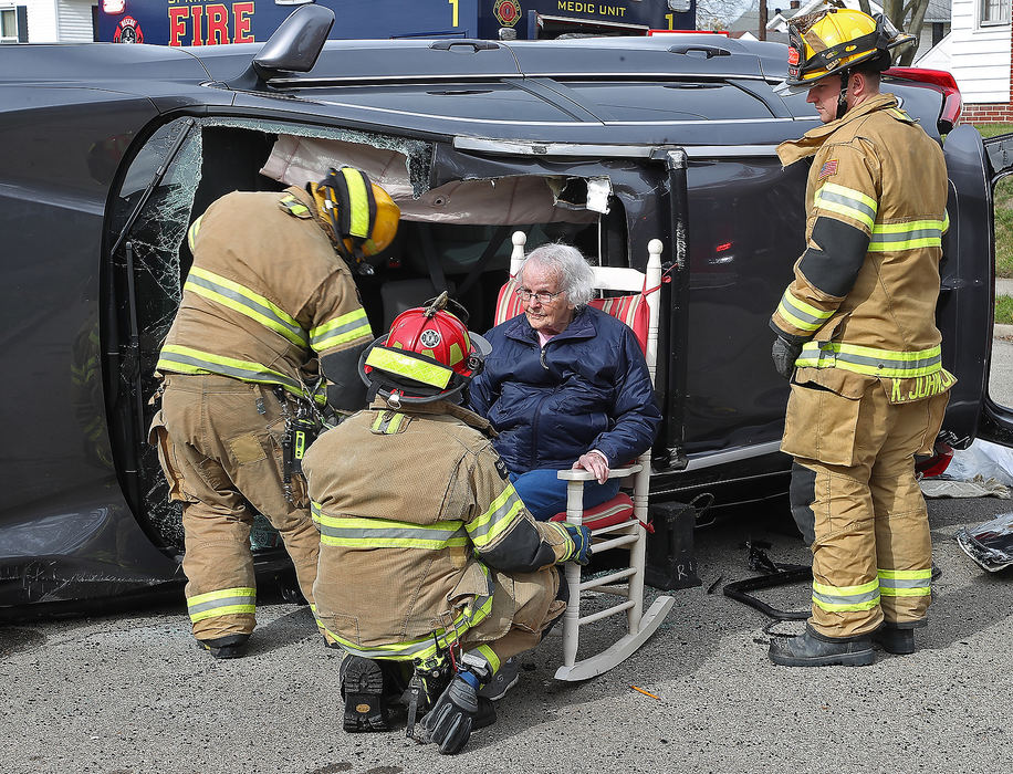 Spot News - 1st place - Members of the Springfield Fire Division got a rocking chair, off a nearby porch, for a woman to sit in as she waits for a stretcher following a two car accident. The woman and her husband had just been rescued from their overturned SUV after the crash at the intersection of Woodside Avenue and Bellevue Avenue. They were transported to the hospital with non-life threatening injuries. Bill Lackey / Springfield News-Sun