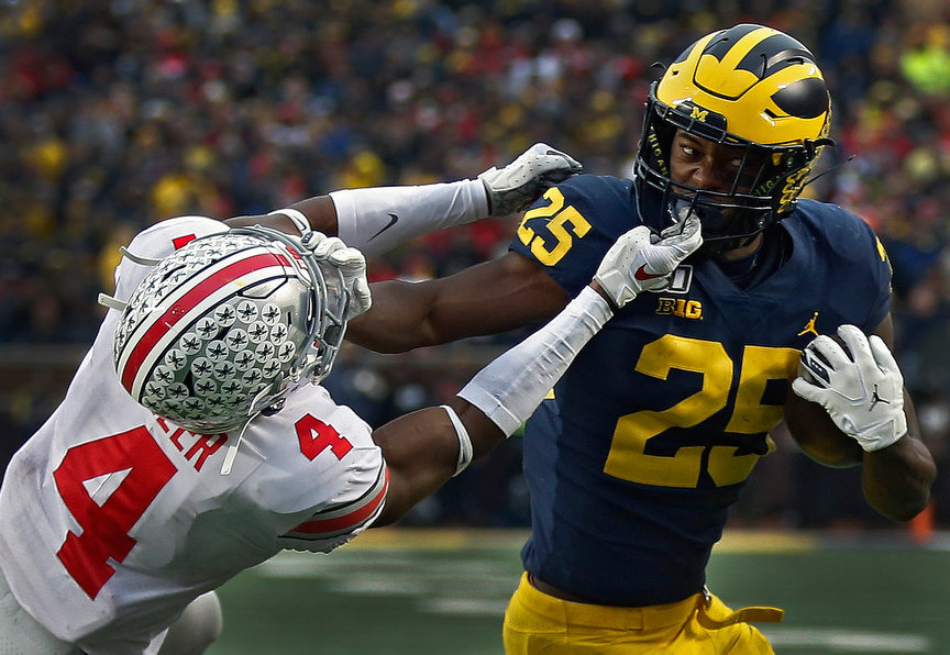 Sports - HM - Michigan Wolverines running back Hassan Haskins (25) fights off Ohio State safety Jordan Fuller (4) to score a two-point conversion during the 4th quarter of their game at Michigan Stadium in Ann Arbor, Michigan. (Kyle Robertson / The Columbus Dispatch)