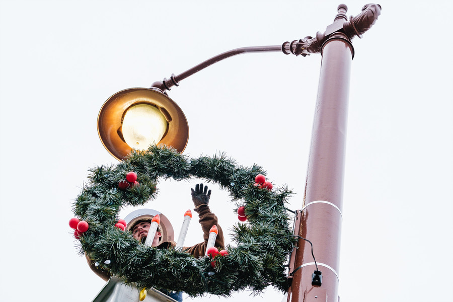 Feature - HM - Nick Ault, a Dover Light & Power electric field division worker, hangs a Christmas wreath along North Tuscarawas Ave  in Dover. Between 65 and 70 wreaths go up across the city each year. (Andrew Dolph / The Times Reporter)