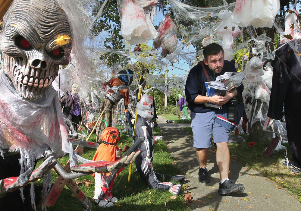 Feature - 2nd placeU.S. Postal Carrier Jason Davis maneuvers around the intricate Halloween display at the 25th Street home of Doug Parker in Cuyahoga Falls. "I think it's cool" said Davis. It kind of brings out the kid in you."  (Phil Masturzo / Akron Beacon Journal)