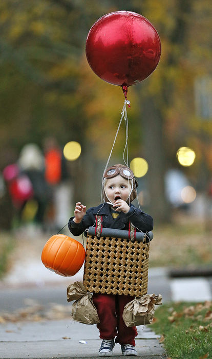 Feature - 2nd place - Tucker Pitts gets an early start on his Halloween candy as he and his mother Ashley Pitts trick or treat in Bexley. The balloon man costume was made by mom and is a hand me down from his brother.  (Chris Russell / The Columbus Dispatch)