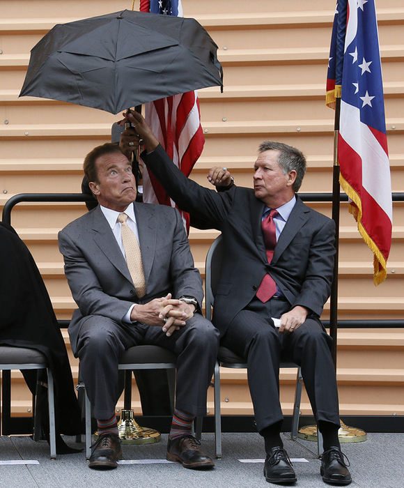 General News - 2nd place - Former California Governor Arnold Schwarzenegger experiences a moment of surprise as Ohio Governor John Kasich accepts an umbrella from a member of law enforcement during the rededication of the Arnold Statue in the courtyard of the Greater Columbus Convention Center. Workers moved the 8-foot, 600-pound bronze statue earlier this month in preparation for the demolition of Veterans Memorial Auditorium.  (Barbara J. Perenic / The Columbus Dispatch)