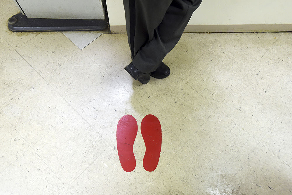 Story - 2nd place - Muskingum County Sheriff Matt Lutz stands next to the footprints placed on the floor for suspects to face the right direction when getting their mugshots taken in the Muskingum County Jail. (Chris Crook / Zanesville Times Recorder)