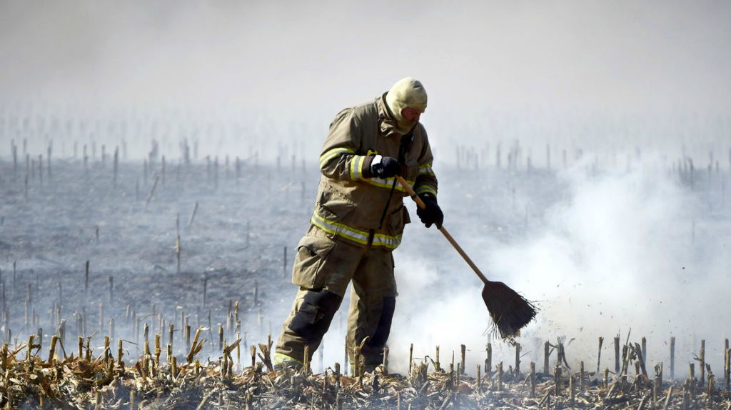 Spot News - 1st place - Celina Firefighter Lt. Jon Schumm uses as broom to brush flames off of dry corn stubble at 9582 US 127. Daniel Melograna / The Daily Standard