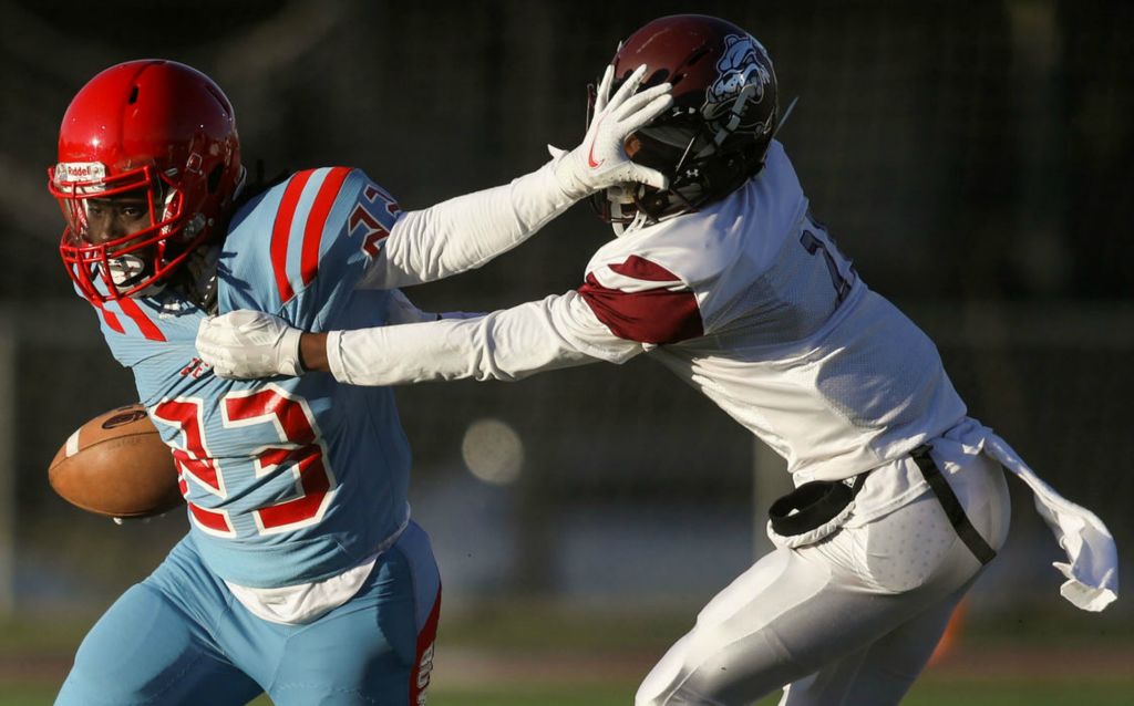 Sports - 2nd place - Bowsher’s Arvell Harrison (left) stiff-arms Scott’s Daveonte Davis (21) at Scott High School in Toledo. Kurt Steiss / The Blade