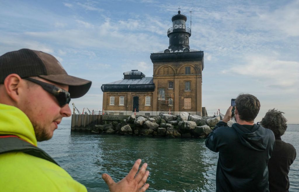 Story - 1st place - Rick Parsons from Buckeye Construction & Restoration rides a boat near the Toledo Lighthouse which is undergoing a transformation. Windows and shutters are being installed and some brick work is being restored. When the project is completed  there will be people at the lighthouse from spring through fall to provide tours.  Jeremy Wadsworth / The Blade