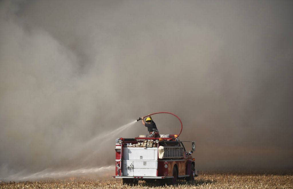 Story - 3rd place - Brad Pontius of the Rockford Fire Department rides on top of the fire truck spraying the field fire at 9582 US 127. Daniel Melograna / The Daily Standard