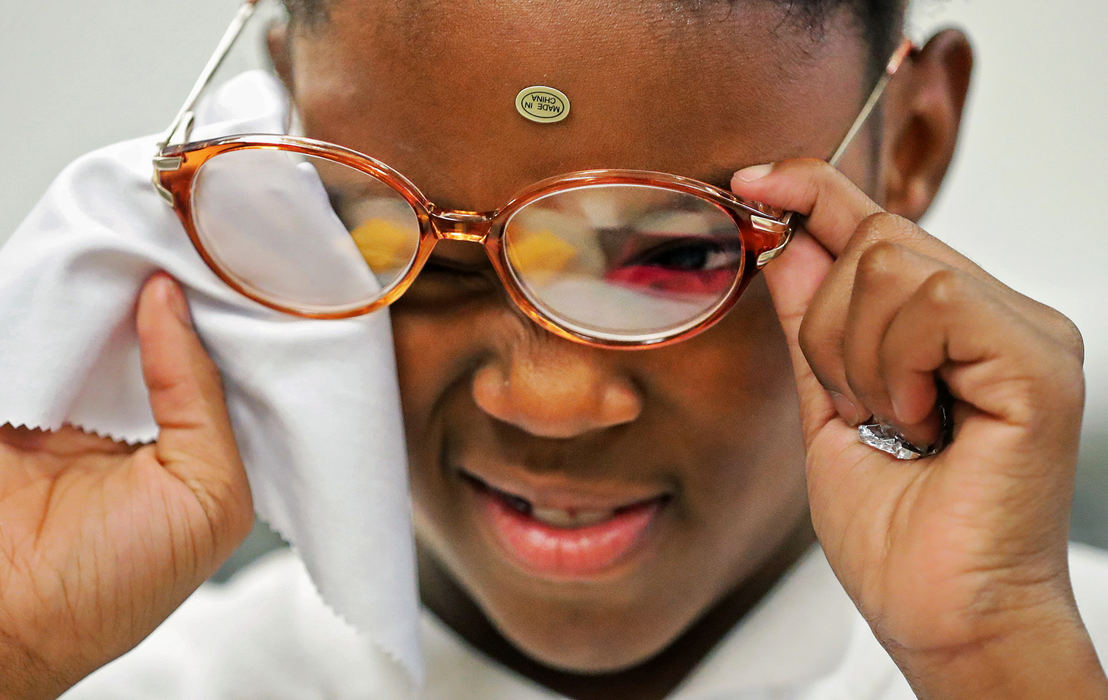 Feature - 1st placeLariyah Moore, 9, wipes away a smudge after having her new glasses fitted by the opticians from Northeast Ohio Eye Surgeons at the I Promise School, in Akron. (Jeff Lange / Akron Beacon Journal)