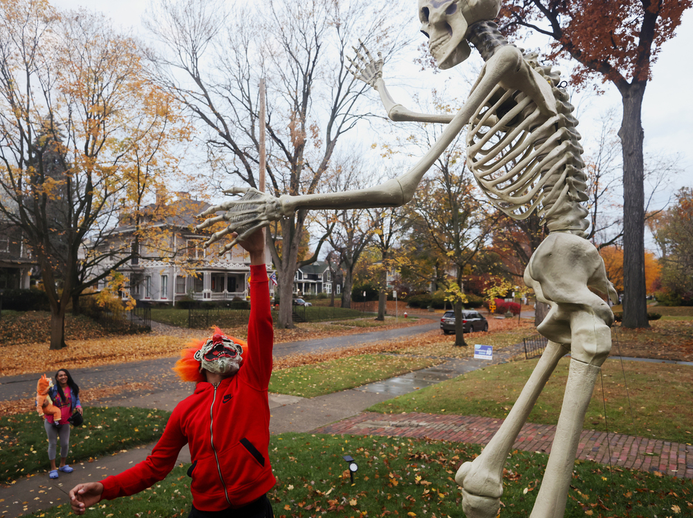 Feature - 2nd place - Jordan Chappell, 13, jumps up to give a large skeleton decoration a high five while trick-or-treating in the Old West End neighborhood of Toledo.  (Kurt Steiss / The Blade)