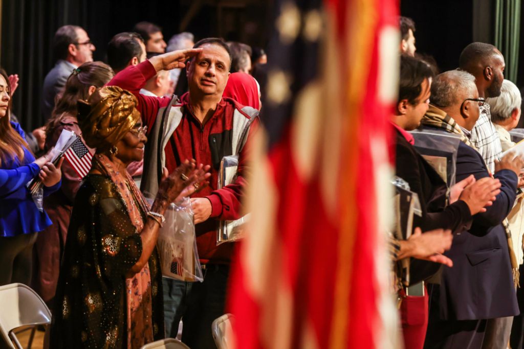 General News - 2nd place - New United States citizen Mohamad Salameh, originally from Israel, turns around to salute the flag while others applaud their accomplishment during a naturalization ceremony at Northwood High School in Northwood.  (Isaac Ritchey / The Blade)