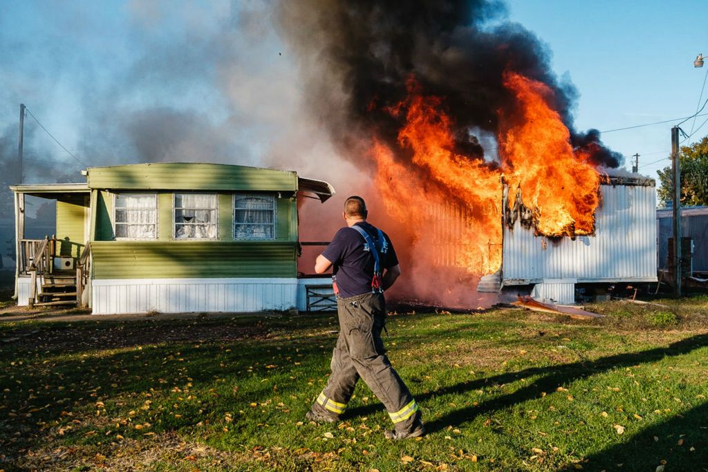 Spot News - 1st place - A New Philadelphia firefighter surveys a vacant trailer on fire at the Quaker Mobile Home Park located at 300 11th St. NW  in New Philadelphia. This was the third trailer fire in the park this year, according to police (Andrew Dolph / The Times Reporter)