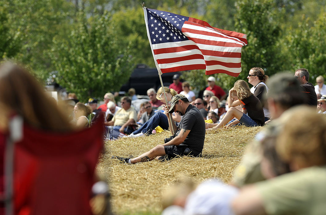 General News - 2nd place - A man holds an American flag as he sits with nearly a thousand people in Freedom Grove in Urbana during a 9/11 Memorial Dedication Ceremony.  (Bill Lackey / Springfield News-Sun)