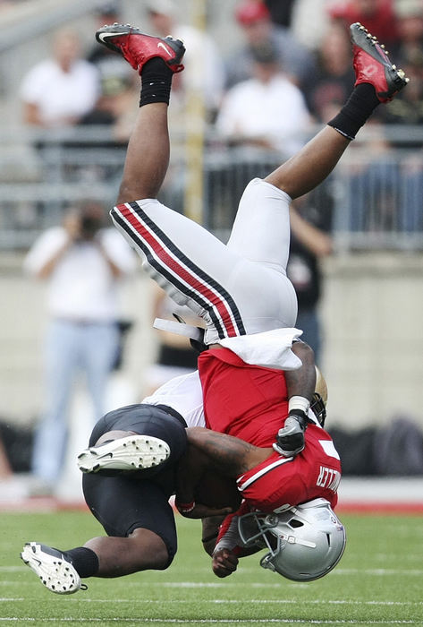 Sports - 3rd place - Colorado Buffalo linebacker Douglas Rippy (3) tackles Ohio State quarterback Braxton Miller (5) in the second quarter of their NCAA football game at the Ohio Stadium in Columbus. (Neal C. Lauron / The Columbus Dispatch)