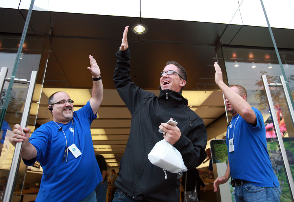 General News - 3rd placeDamon Oney, of Raleigh, North Carolina (center) high-fives two Apple employees after purchasing a new iPhone 5 at the Apple store in Crocker Park in Westlake. ( Lisa DeJong / The Plain Dealer)