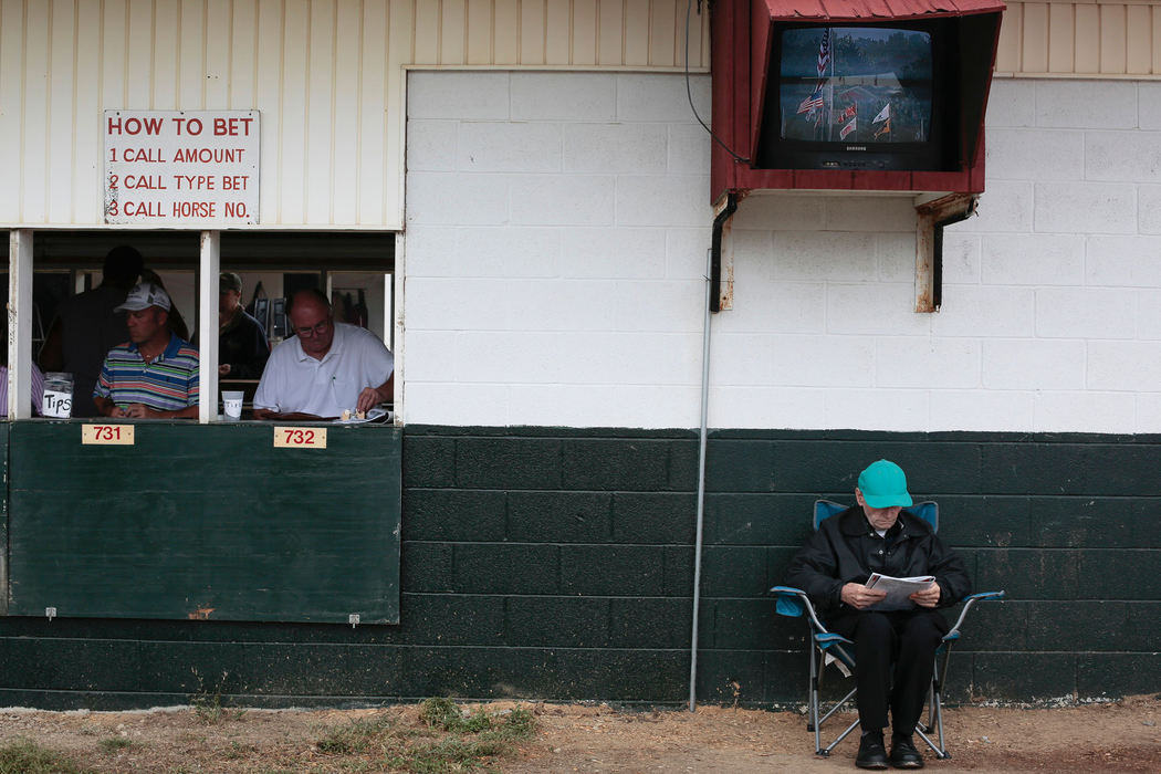 Story - 2nd placeMartin Cianciola (right) of Cleveland reads the race program in front of a betting window during the Little Brown Jug at the Delaware County Fairgrounds. (Joshua A. Bickel / ThisWeek Newspapers)