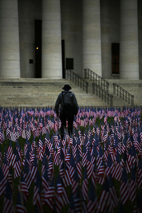 Feature - 1st place - Daniel Thomas, of Upper Arlington, walks through a September 11th memorial on the Ohio Statehouse lawn after taking a photograph. The lawn was covered with 2,999 American flags today to honor each life lost in the attacks on the United States on September 11, 2001. They were arranged in two columns to represent the twin towers with a pentagon-shaped cutout in the center.   (Eamon Queeney / The Columbus Dispatch)